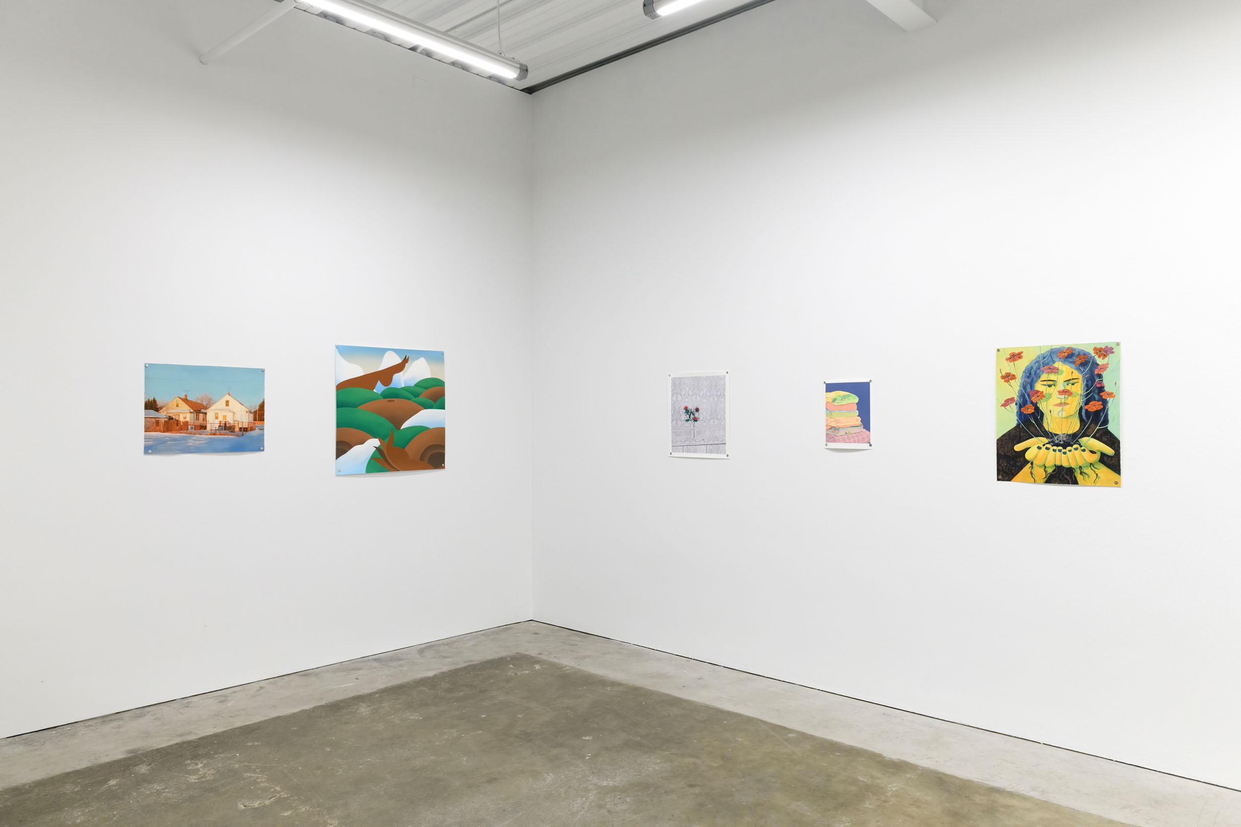 Prints of artworks on a white wall in an art gallery with fluorescent lighting. 